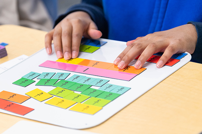 Students use fraction tiles, purchased with ESSER III funding, to assist in visualizing how to find the common denominator when adding fractions.